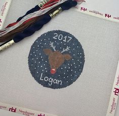 a cross stitch pattern with the name logan written on it and a tassel