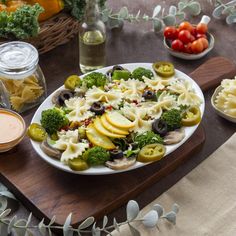 a platter filled with pasta and vegetables on a wooden table next to sauces