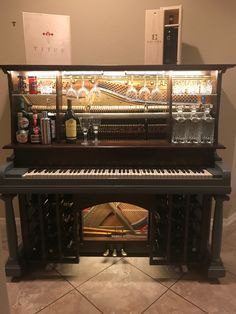 an upright piano with wine glasses and bottles on it