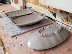 two bowls sitting on top of a wooden table next to each other in front of a wall