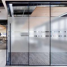 an office with glass walls and wooden flooring in front of the door that leads to a meeting room