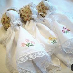 four embroidered cloth napkins with flowers on them sitting on top of a white tablecloth