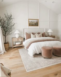 a bedroom with white walls and wood flooring has a large bed in the center