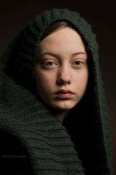 a woman wearing a green hooded sweater and looking at the camera with a serious look on her face