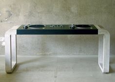 a table with two turntables on it in front of a concrete wall and cement floor