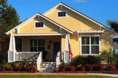 a yellow house with an american flag on the front porch