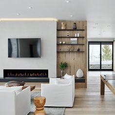 a living room with white furniture and a flat screen tv mounted above the fire place