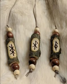 three necklaces with different designs on them sitting on a white fur covered surface,