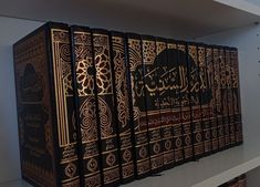 a row of black books sitting on top of a white shelf