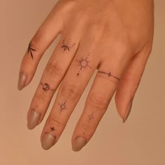 a woman's hand with an arrow and stars tattoo on her left ring finger