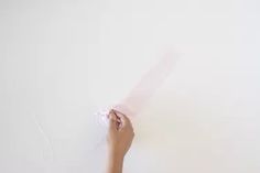 a person holding something in their hand on a white wall with no one around it