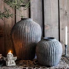 two vases sitting on top of a table next to a candle