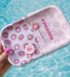 a person holding a pink donut shaped tray in their hand with the lid open