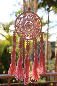 a pink and white dream catcher hanging from a tree