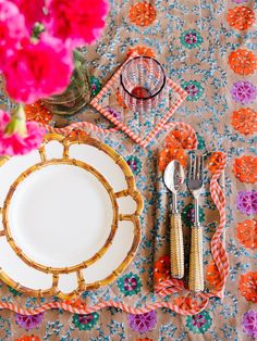 a place setting with flowers on the table and napkins, silverware and utensils