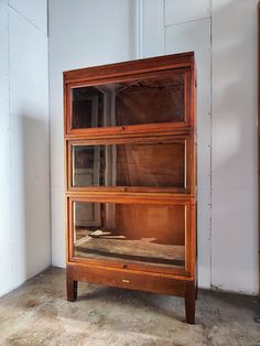 an old wooden cabinet with glass doors on the front and bottom shelves, in a room