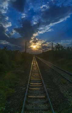 the sun is setting over an empty train track