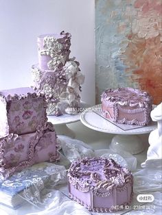 there are three cakes on the table and one cake is covered in purple icing