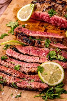 steak sliced up on a cutting board with lemons and parsley