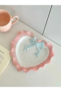 a pink and white heart shaped plate next to a cup