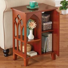 a small wooden table with a vase and some books on the shelf next to it