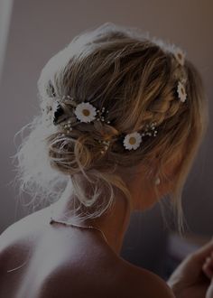 the back of a woman's head with flowers in her hair and pearls on it