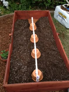 a garden box filled with dirt and water in the ground next to a white watering hose