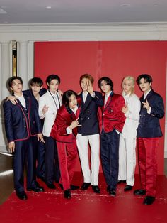 a group of young men standing next to each other in front of a red wall