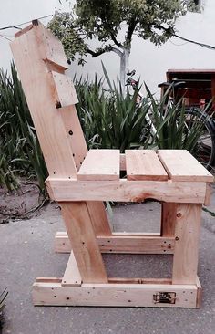 a wooden chair sitting on top of a cement ground next to grass and flowers in the background