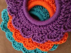 four crocheted coasters are stacked on top of each other in different colors