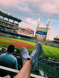 two people are sitting in the bleachers at a baseball game with their feet up