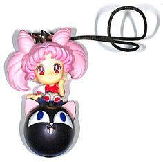 a black and white cat with pink hair sitting on top of a keychain