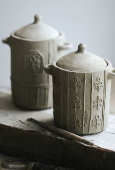 two ceramic pots sitting on top of a wooden table