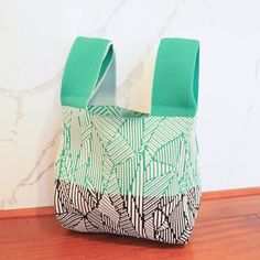 a green and white bag sitting on top of a wooden table next to a wall