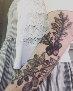 a woman's arm with leaves and acorns on it