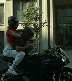 a man riding on the back of a motorcycle next to a woman wearing a helmet