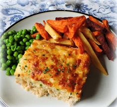 a white plate topped with meat and veggies next to potato wedges on top of a table