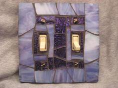 a decorative light switch cover with purple and blue tiles