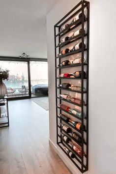 a wall mounted wine rack filled with bottles in a living room next to a window