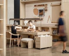 two people are sitting at a table in a room with shelves and shelvings