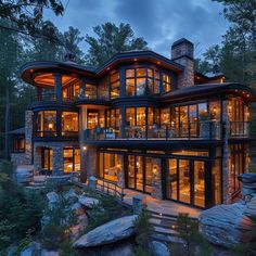 a large house with lots of windows and lights on it's sides in the woods