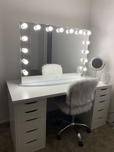 a white desk topped with a vanity mirror and lots of lights on top of it