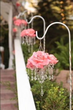 pink roses are hanging from the side of a white pole with crystal chandeliers