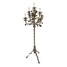 a tall metal candle holder with five candles on it's base and four flowers in the center