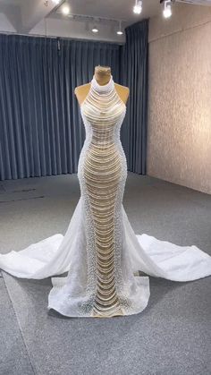 a dress on display in a room with curtains and lights behind the mannequin