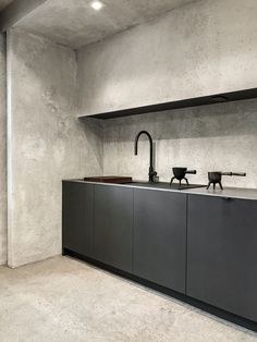 a kitchen with concrete walls and black cabinets