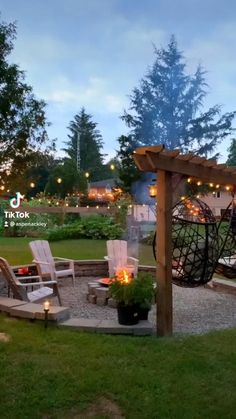 an outdoor patio with chairs, lights and fire pit in the middle of it at dusk