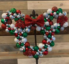 a mickey mouse christmas wreath with red, white and green ornaments on a metal stand