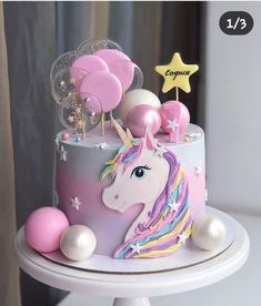 a cake decorated with pink, white and blue icing has a unicorn on it