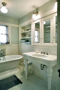 a white bath tub sitting next to a sink in a bathroom under two lights and a window